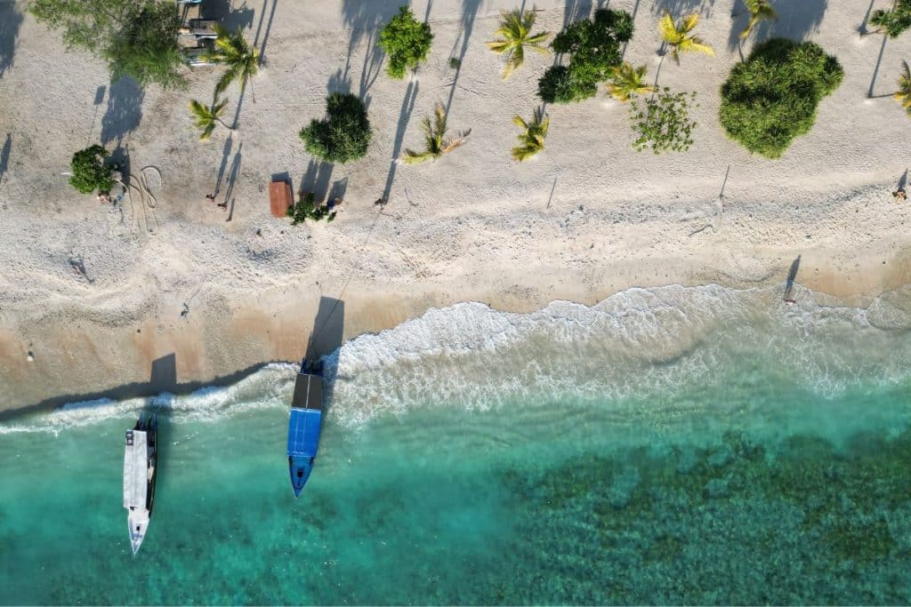 Small boat anchored near Gili Meno’s beach in clear blue water