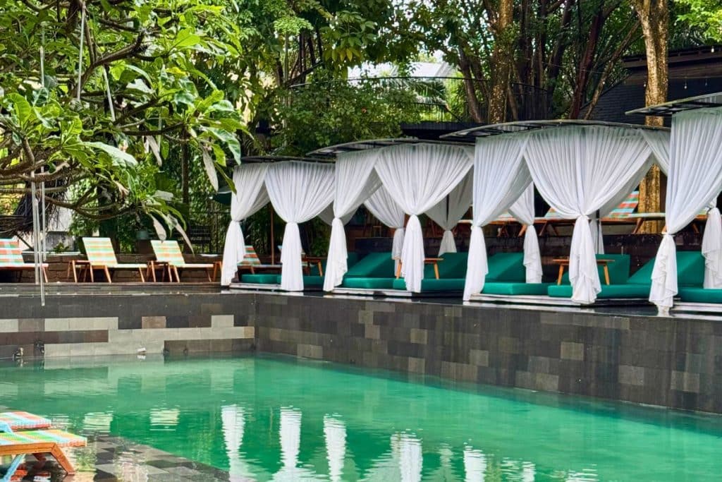 Swimming pool surrounded by loungers and palm trees at Titi Batu in Ubud