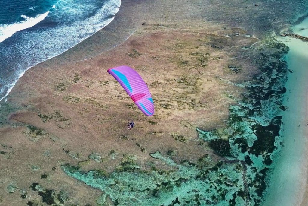 Paraglider flying above the cliffs of Uluwatu with ocean views