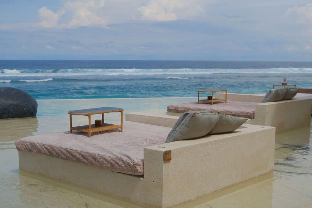 Uluwatu beach club with pool, palm trees, and ocean view