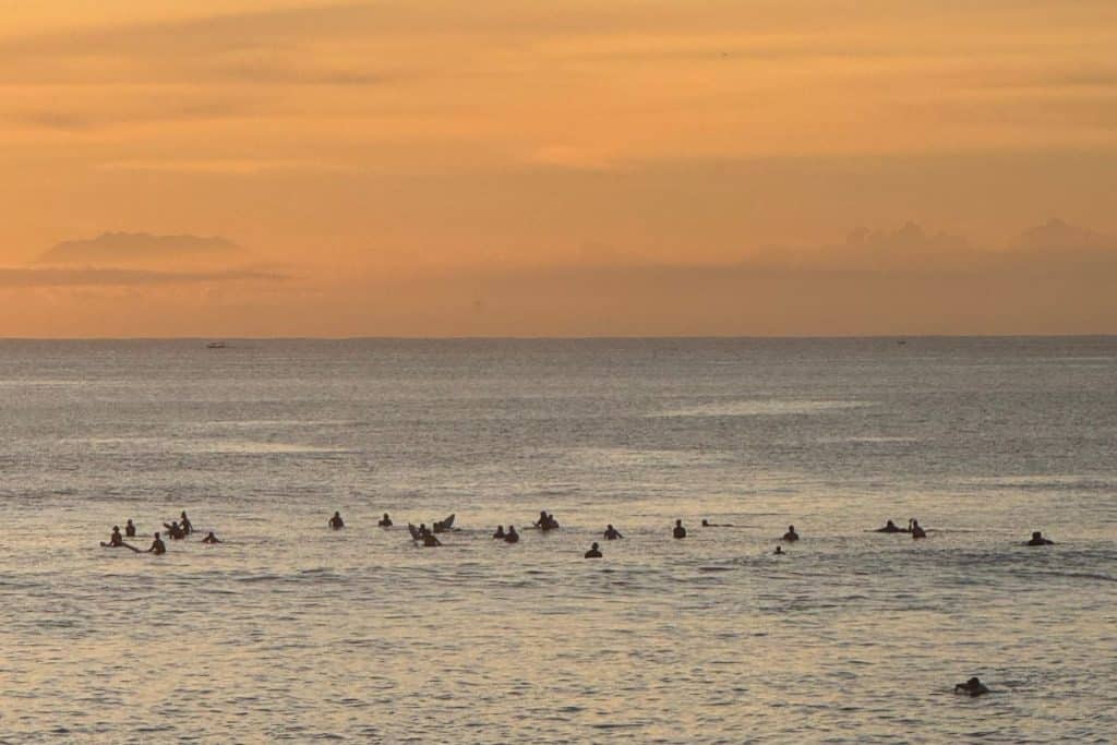 Surfer walking along the shore at sunset in Uluwatu, Bali