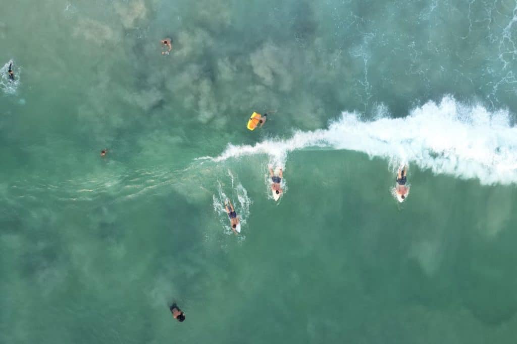 Drone view of surfers riding waves in Uluwatu