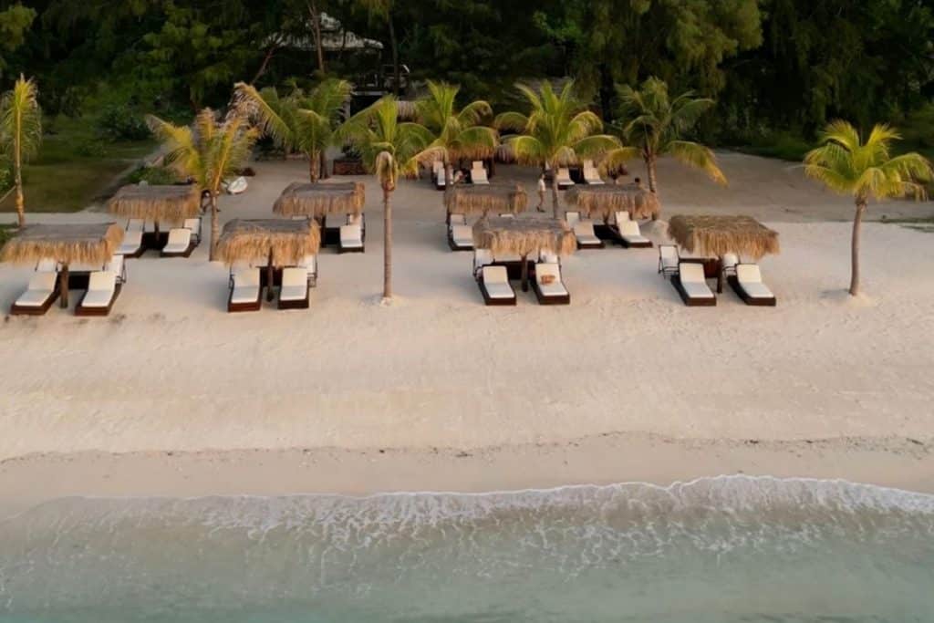 Aerial view of pristine white sandy beach and turquoise waters at the Gili Islands with scattered boats and lush greenery.