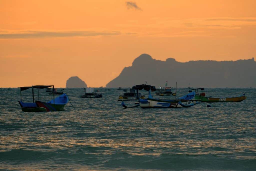 Sunset beach with boat Indonesia golden sky calm ocean and silhouette of traditional boat
