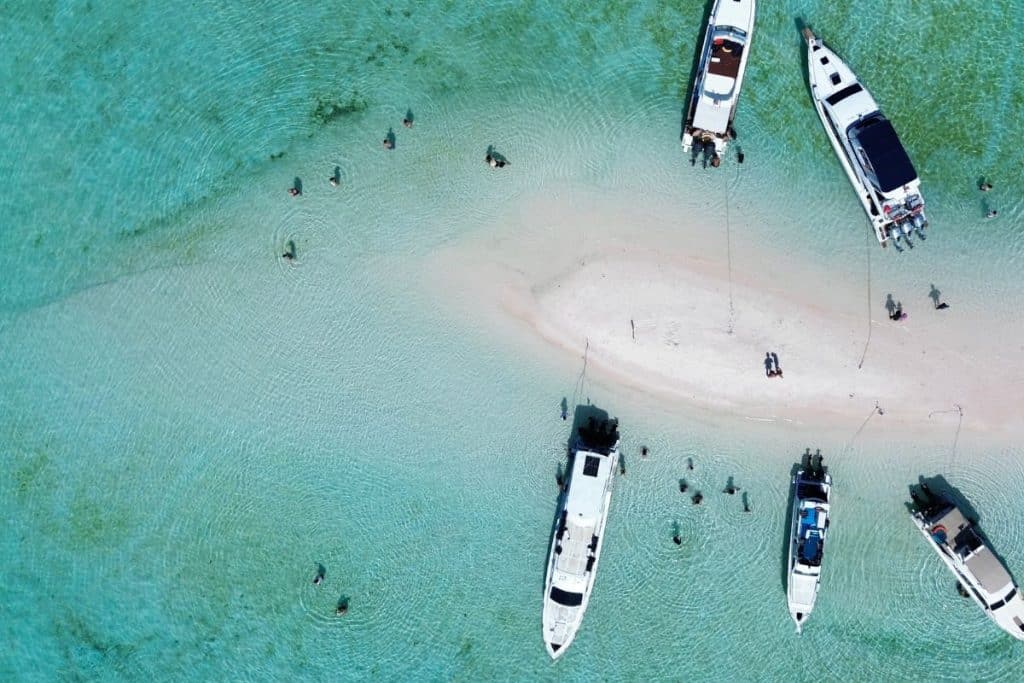 Aerial view of Taka Makassar, a small curved sandbar surrounded by crystal-clear turquoise water in Komodo National Park.