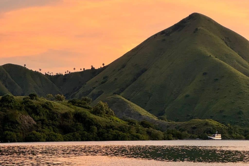 Golden-orange sunset casting light over the ocean and islands of Flores, Indonesia.