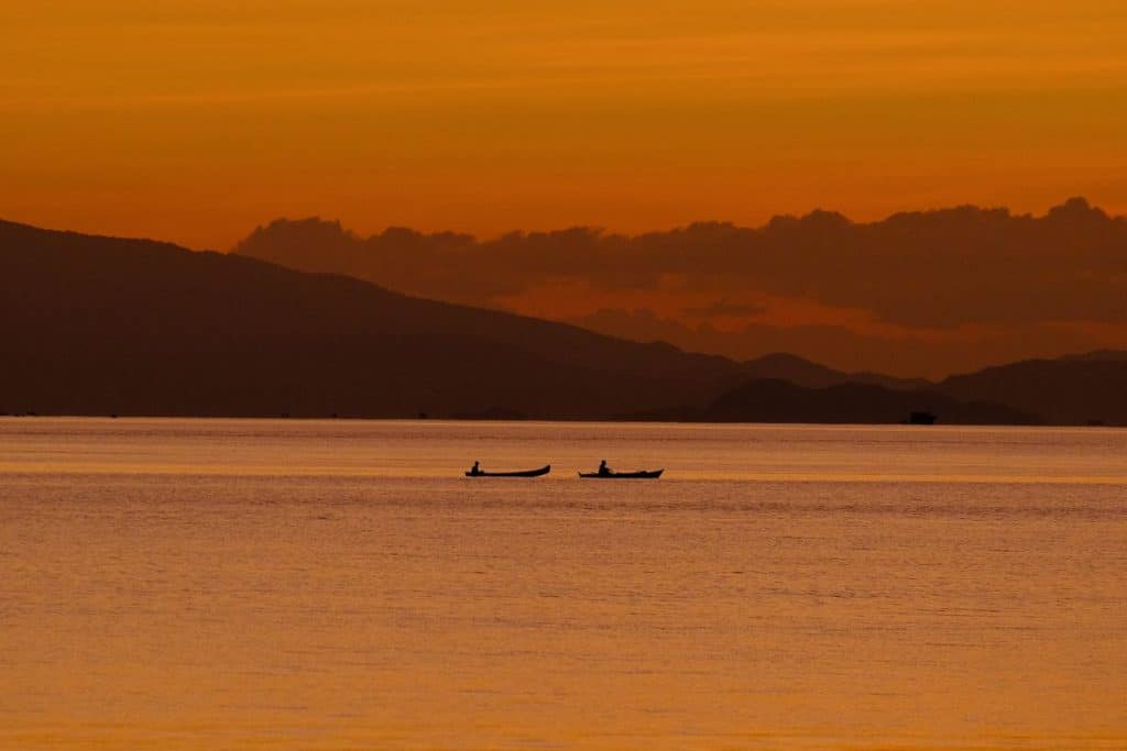 Kayaking at sunset in Flores Indonesia with golden sky reflections and calm ocean waters