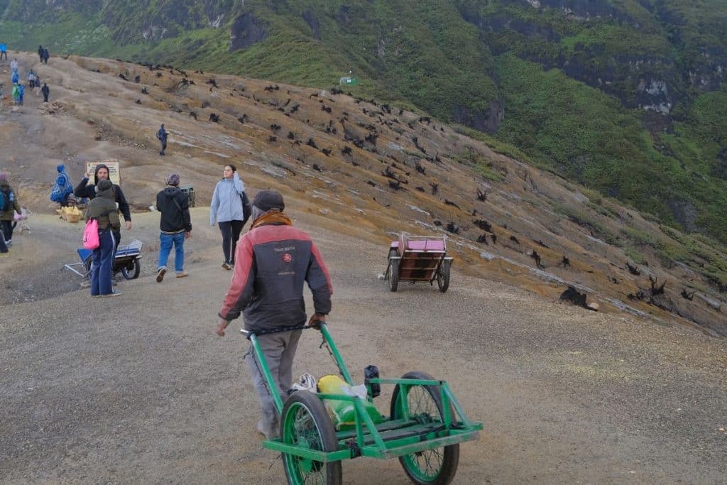 Hikers climbing Mount Ijen at night with headlamps and gas masks