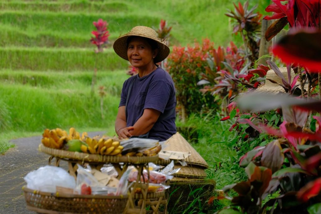 Local fruit vendor in Jatiluwih, Bali, surrounded by tropical produce