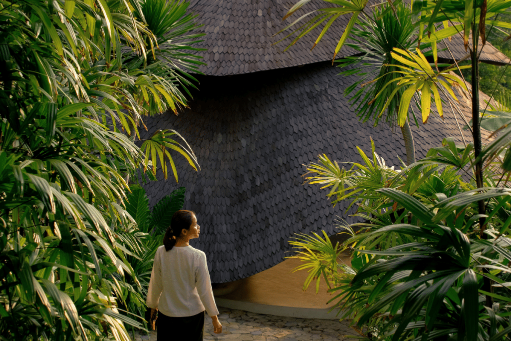 Mambo Lombok staff member walking between bamboo villas