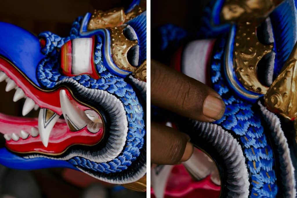 Close-up details of hand-painted Balinese wood carving mask with intricate textures and colors