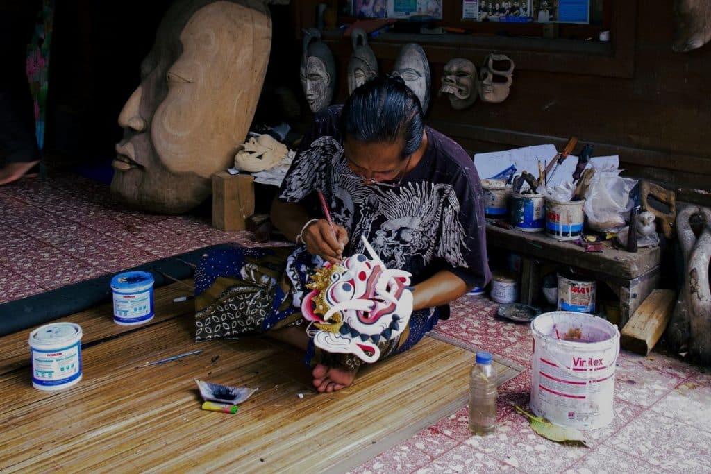 Anom Balinese wood carving artist working on a traditional mask in his Bali workshop