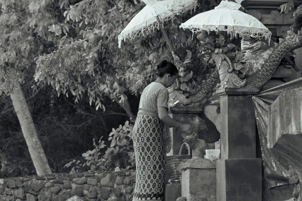 Balinese woman praying inside a temple during Kuningan celebrations in Bali.