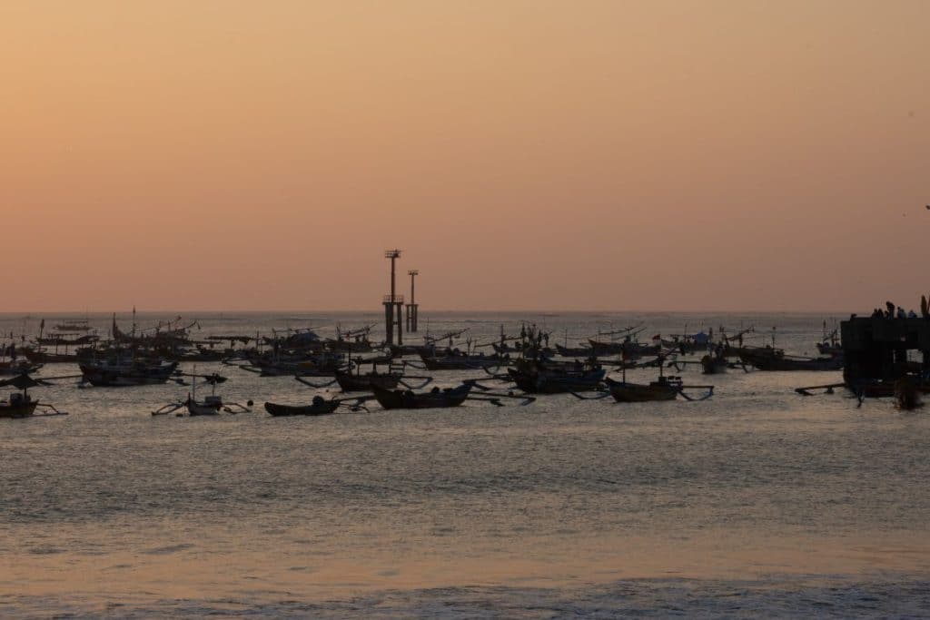 Sunset over Jimbaran Bay and its fishing harbour in Bali