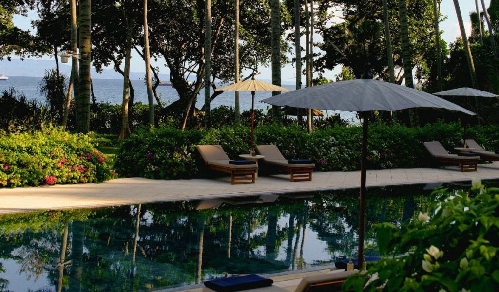 Amankila Bali pool near the beach with palm trees