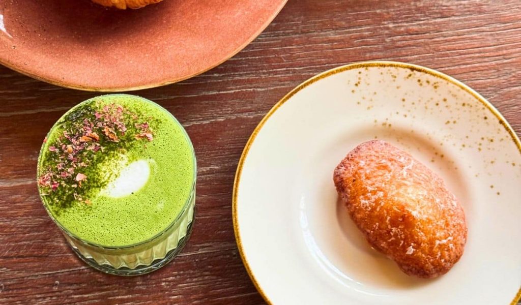 A vibrant matcha latte served with assorted pastries at Fleur café in Bali.