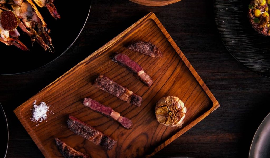 Assorted Mexican-style dishes from Chupacabras, including tacos, grilled meats, and colorful sides served on a rustic wooden table.