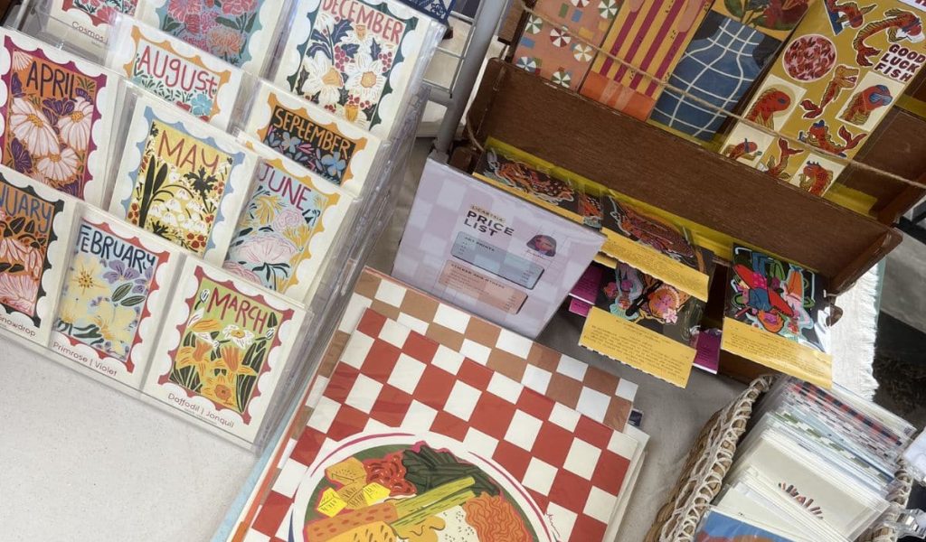 Handmade postcards and illustrated souvenirs displayed by a local vendor at a market in Uluwatu