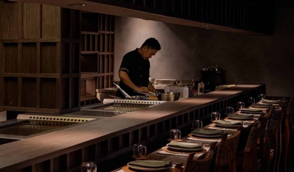 Chef cooking at MORI Restaurant, preparing refined dishes with open-kitchen techniques.