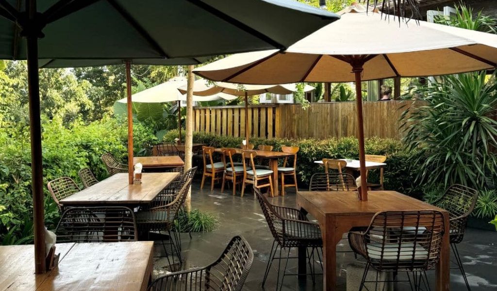 Outdoor seating area at Satu Satu Café in Uluwatu surrounded by tropical greenery