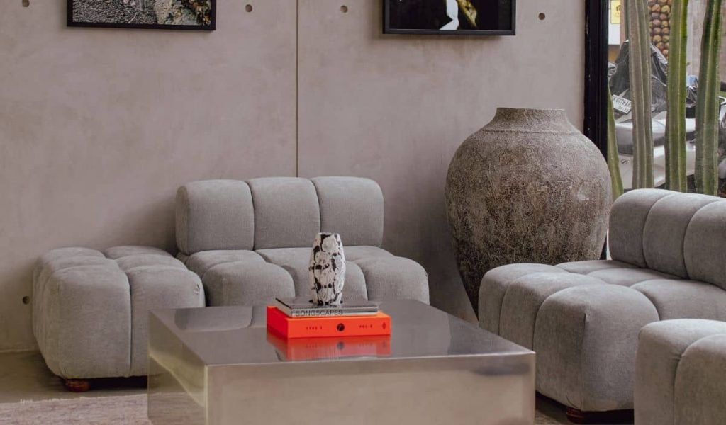 Industrial-style concept store interior at The House of Merchants in Bingin featuring raw concrete, floor-to-ceiling windows, and metal furniture